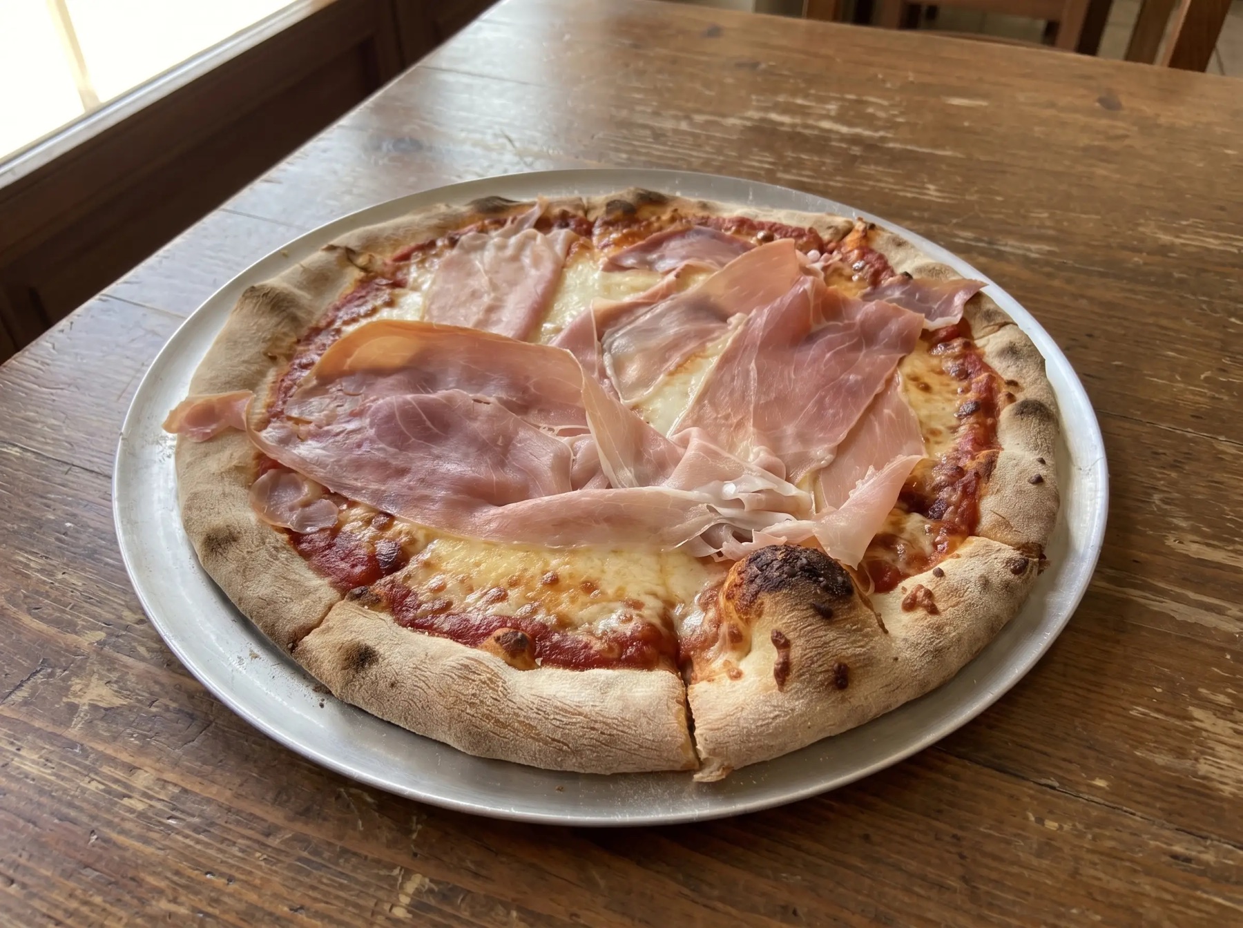Hand-made prosciutto pizza on a metal tray at Italian Corner