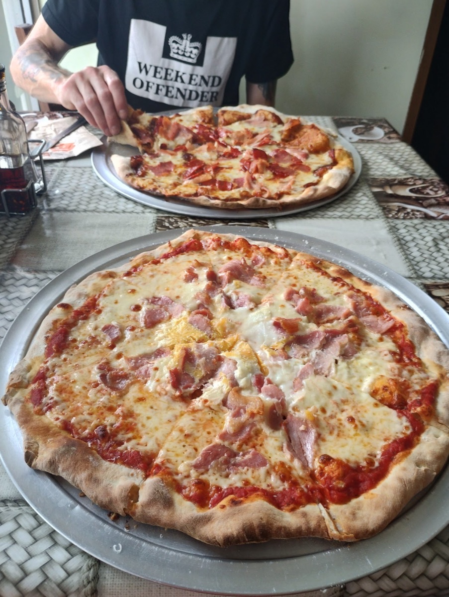 Two freshly made pizzas served on trays at Italian Corner